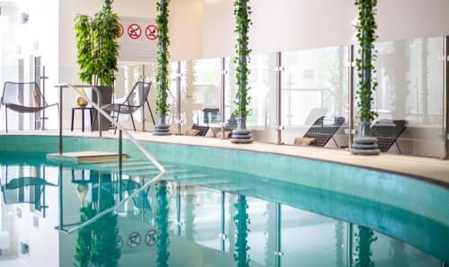 a pool in a hotel with chairs and plants at Crowne Plaza Felbridge - Gatwick, an IHG Hotel in East Grinstead