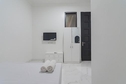 Habitación blanca con puerta negra y TV. en Family Homestay Syariah Cirebon Mitra RedDoorz en Cirebon