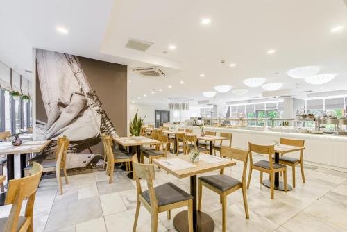 a restaurant with wooden tables and chairs at Centrum Zdrowia i Wypoczynku Ikar in Kołobrzeg