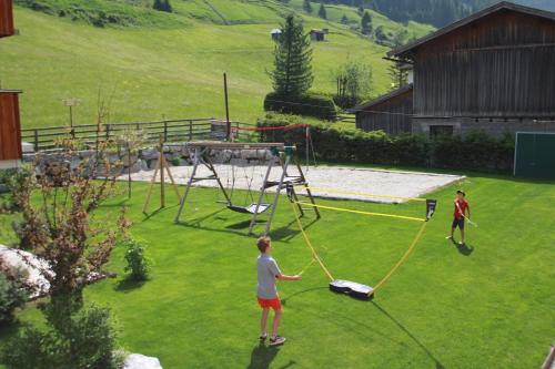 two people standing in a yard with a swing at Ferienwohnung Alte Post in Sankt Leonhard im Pitztal
