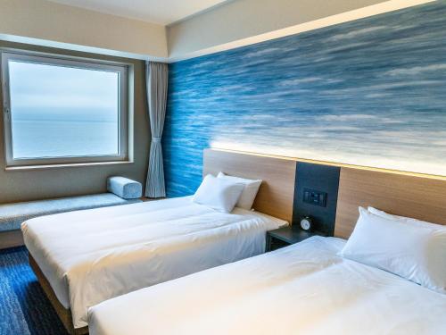 a hotel room with two beds and a window at Hakodate Yunokawa Onsen Umi to Akari Hewitt Resort in Hakodate
