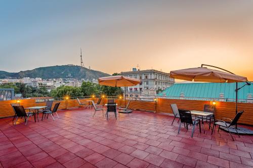 a rooftop patio with tables and chairs and umbrellas at Monument1880 in Tbilisi City