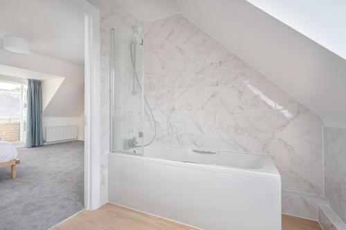 a bathroom with a white tub and a marble wall at 3 Bedroom Jesus Green Townhouse with Parking in Cambridge