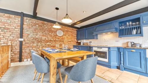 een keuken met blauwe kasten en een houten tafel en stoelen bij Host & Stay - The Burrow in Alnwick