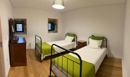 a room with two beds with green accents at Quinta Casa do Retiro in Penalva do Castelo