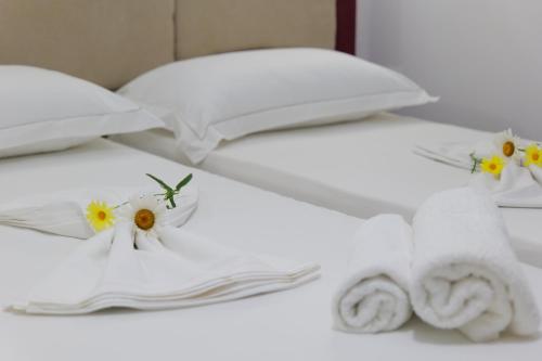 two white beds with towels and flowers on them at Villa JOSANA in Sarandë
