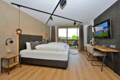 a bedroom with a bed and a desk and a television at Pension Waldkristall in Frauenau