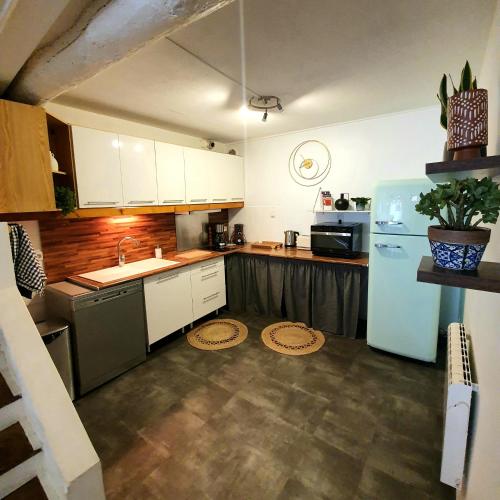 La cuisine est équipée de placards blancs et d'un réfrigérateur bleu. dans l'établissement La Caponnière, à Carcassonne