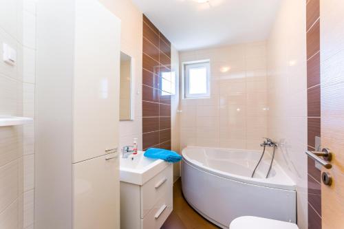 biała łazienka z wanną i umywalką w obiekcie Dragan K1 w Medulinie