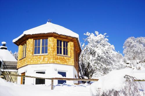 a yellow building in the snow with snow covered trees at Biohotel Eggensberger in Füssen