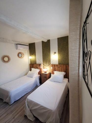 deux lits dans une chambre d'hôtel avec des draps blancs dans l'établissement La Caponnière, à Carcassonne