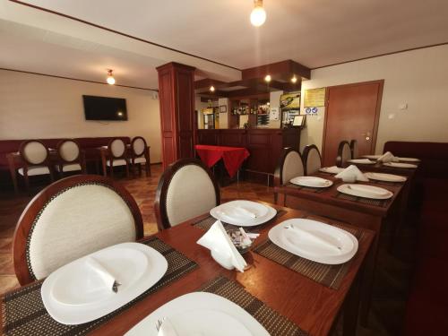 a dining room with a table with white plates on it at Pensiunea Memy in Buşteni