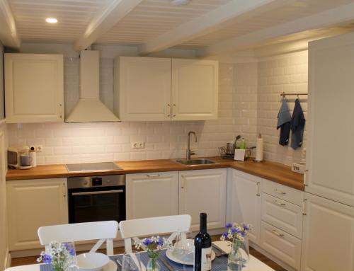 a kitchen with white cabinets and a table with chairs at Ferienwohnung Landfein in Quarnstedt