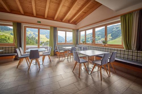 a dining room with tables and chairs and windows at Am Mitteregghof in Saalbach Hinterglemm