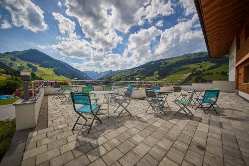 a group of chairs and tables on a patio with mountains at Am Mitteregghof in Saalbach Hinterglemm