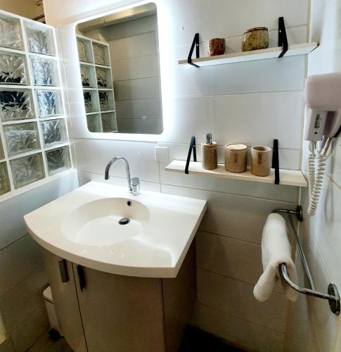 une salle de bain blanche avec un lavabo et un miroir dans l'établissement La Caponnière, à Carcassonne