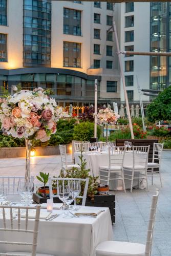 a group of tables with white chairs and flowers at Radisson Blu Hotel Bucharest in Bucharest