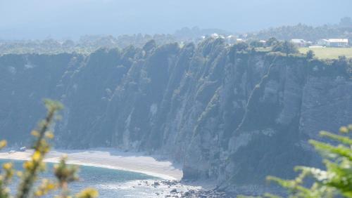 a cliff with a beach next to the ocean at HOTEL LA CASA DE LAS CAMELIAS in Busto
