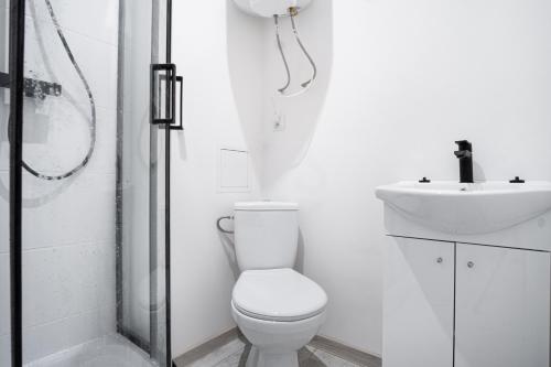 a white bathroom with a toilet and a sink at Revolution Aparts - Rewolucji 27 in Łódź