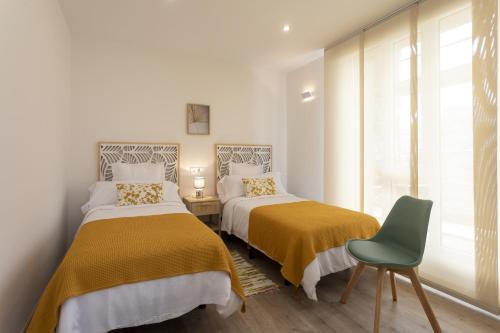 1 dormitorio con 2 camas y silla verde en Playa Ribeiría apartamento vacacional, en Tapia de Casariego