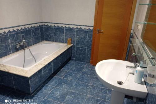 a blue tiled bathroom with a tub and a sink at Apartamento de 3 dormitorios en Camariñas in Camariñas