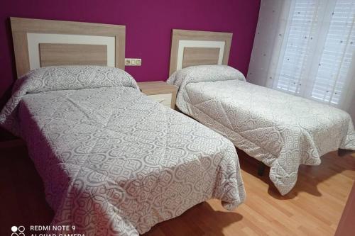 two beds in a bedroom with purple walls at Apartamento de 3 dormitorios en Camariñas in Camariñas