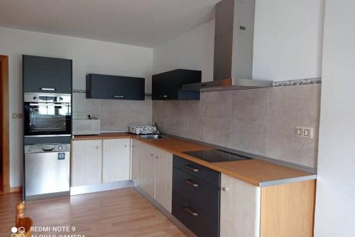 a kitchen with white cabinets and black appliances at Apartamento de 3 dormitorios en Camariñas in Camariñas