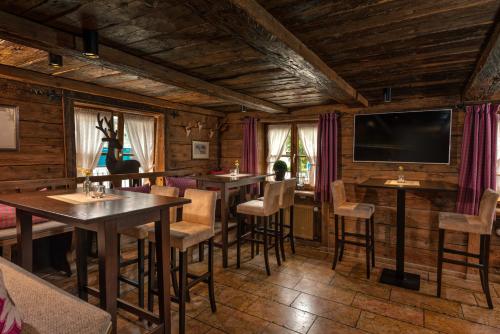 a restaurant with tables and chairs and a flat screen tv at Hotel Hirsch in Oberstaufen