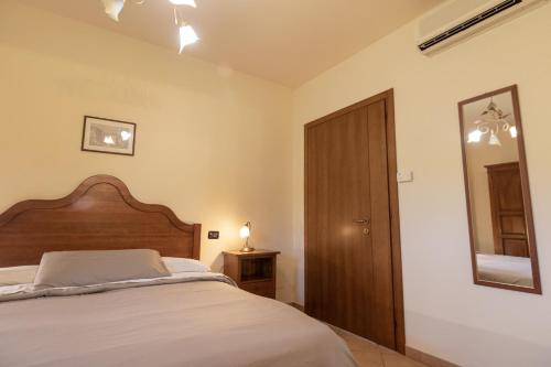 a bedroom with a bed with a wooden headboard and a mirror at Residenza Il Falchetto in Assisi