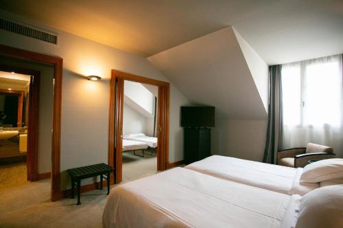 a hotel room with two beds and a mirror at Hotel Sercotel Ciudad de Oviedo in Oviedo