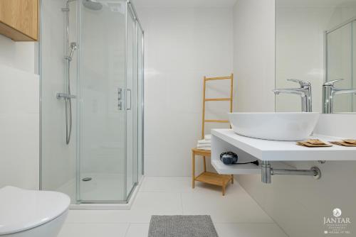 ein weißes Badezimmer mit Waschbecken und Dusche in der Unterkunft Pearl Apartments Rogowo by Jantar Apartamenty Kołobrzeg in Rogowo