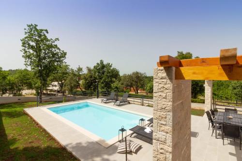 a swimming pool in a yard with a table and chairs at Beautiful villa Foska with private Pool near the beach in Marčana