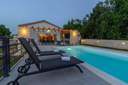 a swimming pool with a chair next to a house at Beautiful villa Foska with private Pool near the beach in Marčana