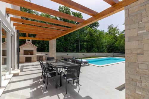 a patio with a table and chairs and a swimming pool at Beautiful villa Foska with private Pool near the beach in Marčana