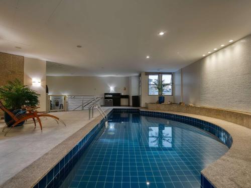 a swimming pool in a hotel with a blue tile floor at Mercure Belo Horizonte Lourdes in Belo Horizonte