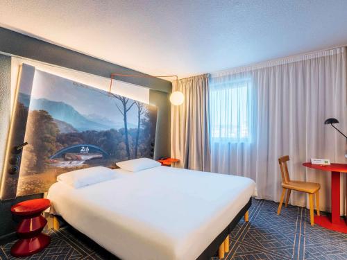 ルマンにあるアイビス スタイルス ルマン ガール スッドの大きなベッドと壁に絵画が備わるホテルルームです。
