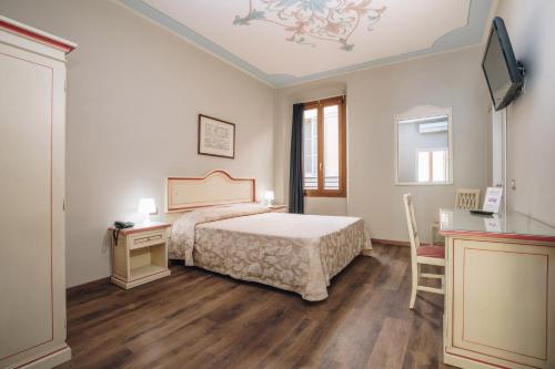 um quarto com uma cama, uma secretária e uma televisão em Hotel Astoria em Cremona