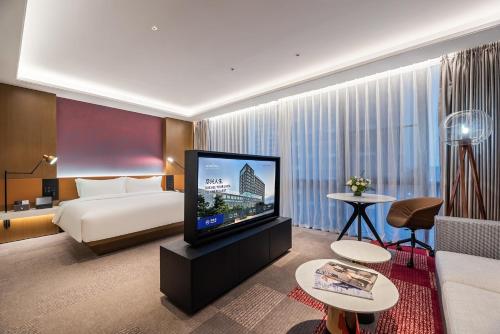 a hotel room with a bed and a flat screen tv at Novotel Dongguan Songshan in Dongguan