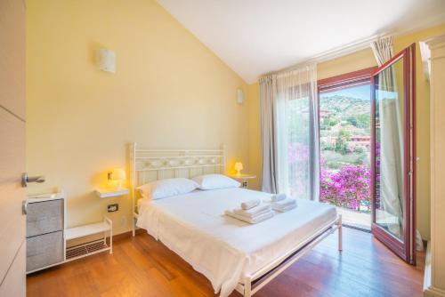 1 dormitorio con cama blanca y ventana grande en Villa Luna . Chia Eden Rock . Wifi AC, en Riva dei Pini