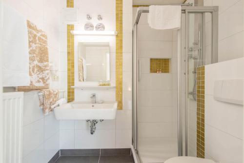 a white bathroom with a sink and a shower at Hotel Garni Lichtquelle in Bad Füssing