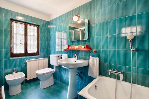 Baño de azulejos azules con aseo y lavamanos en Chalet Casa dei Nonni, en Ceppo Morelli
