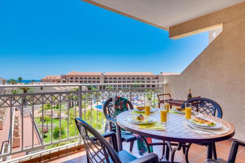 a table and chairs on a balcony with a view of the ocean at Tenerife South Apartments in Playa de las Americas