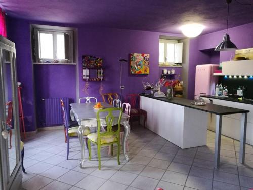 una cucina con pareti viola, tavolo e sedie di Casa Pressenda Apartment a La Morra