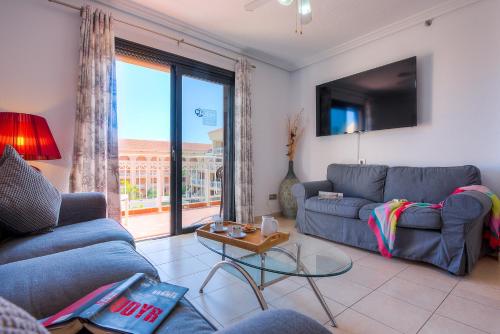 a living room with a blue couch and a table at Tenerife South Apartments in Playa de las Americas