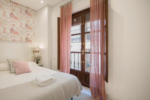 una camera da letto con un letto con tende rosa e una finestra di Lateral Suite Rodo a Siviglia
