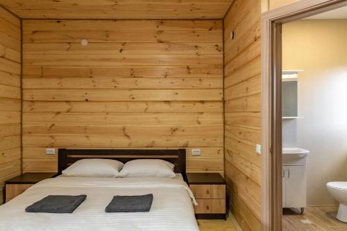 a bedroom with a bed in a wooden wall at Sonyachni bungalo in Melʼniki