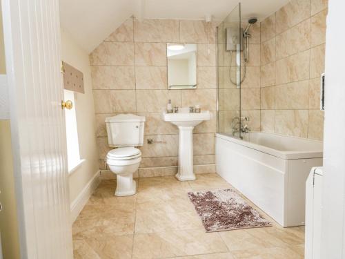 a bathroom with a toilet and a sink and a bath tub at Chapel Cottage in Redcar