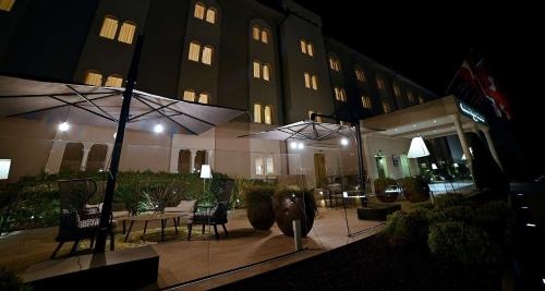 a hotel at night with tables and chairs and umbrellas at Best Western Grand Hotel Guinigi in Lucca