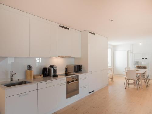 a kitchen with white cabinets and a table with chairs at Top City Center Apartments location next to Lion Monument in Luzern