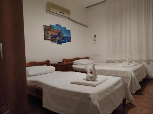 a room with two beds with white sheets at meltem pansiyon in Kas